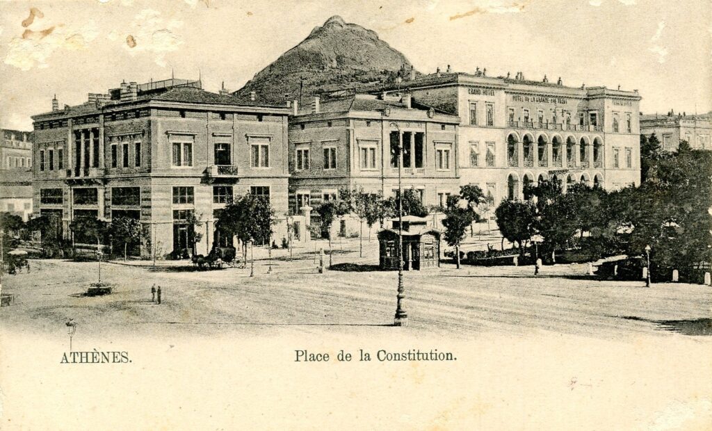 A 1901-postcard depicting the Syntagma Square and, on the right, the “Grand Hôtel”, with the Mount Lycabettus in the background. The image captures the urban development of the capital and the architectural character of the square before the major urban planning changes of the 20th century.